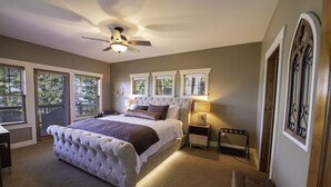 Ein Schlafzimmer mit einem großen Bett, einem Deckenventilator und mehreren Fenstern.