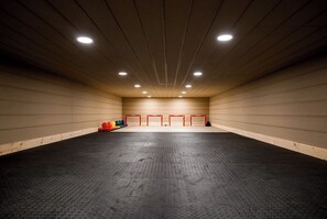 Un amplio espacio interior con piso de caucho negro, paredes de madera e iluminación en el techo.