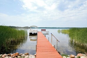 Un muelle de madera se adentra en un lago tranquilo, con un bote amarrado al final.