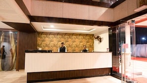 A reception desk with two staff members, a patterned wall, and a glass partition.