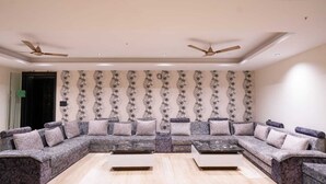 A spacious living room with a large L-shaped sectional sofa, two ceiling fans, and a patterned wallpaper.