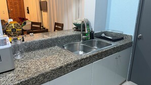 A kitchen with granite countertops, stainless steel sink, and white cabinets.