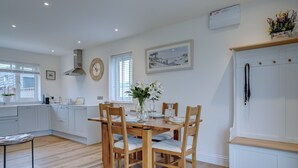 Una cocina moderna con una mesa de comedor de madera, armarios blancos y un banco empotrado.