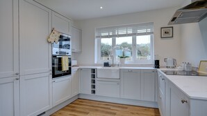 Una cocina moderna con armarios blancos, horno integrado y ventana con vistas al exterior.