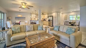 A spacious living room with a beige sofa set, a glass coffee table, and a ceiling fan. - Private Oasis at the Beach with HEATED Pool, Dock and Boat…..Dolphin paradise! (Cocoa Beach)