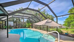 A covered swimming pool with a glass ceiling, surrounded by greenery and a clear sky. - Private Oasis at the Beach with HEATED Pool, Dock and Boat…..Dolphin paradise! (Cocoa Beach)