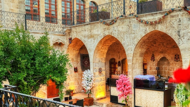 Un cortile con archi in pietra, posti a sedere all'aperto e piante in vaso.