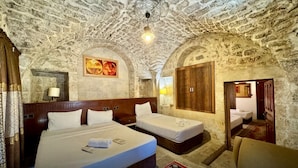 Una stanza con due letti, un armadio in legno, un quadro e un soffitto in pietra.