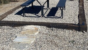 An outdoor seating area with a metal table and benches, a stone fire pit, and a chimney. - Quiet Country Setting (Bozeman)