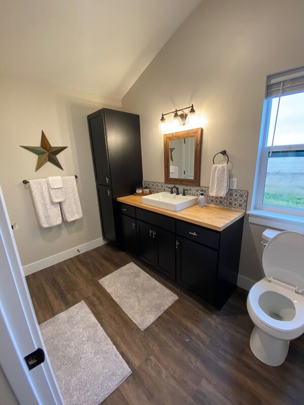 A modern bathroom with a wooden vanity, a large mirror, and a star decoration on the wall. - Quiet Country Setting (Bozeman)