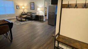 A modern living room with a ceiling fan, a dining area with a table and chairs, and a kitchen area with a refrigerator and a TV mounted on the wall. - Quiet Country Setting (Bozeman)