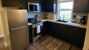 A modern kitchen with dark cabinets, stainless steel appliances, and a patterned rug. - Quiet Country Setting (Bozeman)