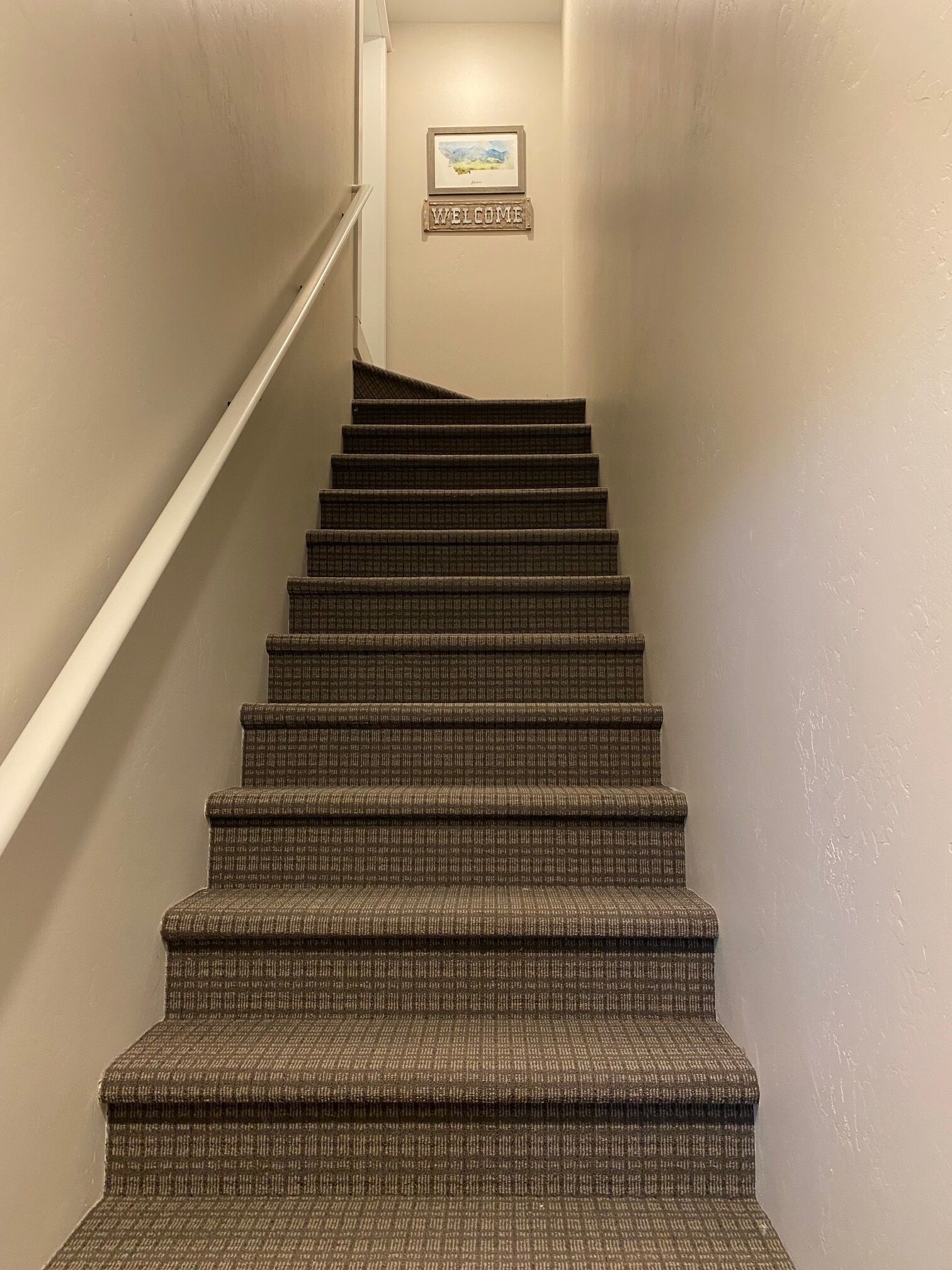 A carpeted staircase with a 'WELCOME' sign at the top.