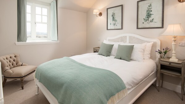 Ein Schlafzimmer mit einem großen Bett, einem Sessel, einem Nachttisch und zwei Wandlampen.
