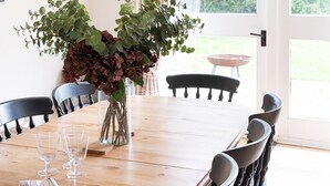 A dining area with a wooden table, black chairs, and a vase of flowers. - The Coach House, Pentland Hills - Sleeping 6 Guests in 3 Bedrooms, Dog Friendly (Nine Mile Burn)