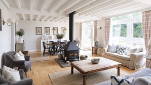 A cozy living room with a fireplace, a dining area, and a sofa set. - The Coach House, Pentland Hills - Sleeping 6 Guests in 3 Bedrooms, Dog Friendly (Nine Mile Burn)