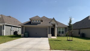 A residential house with a garage, a driveway, and a small lawn. - Skip the gameday/ graduation gridlock (Bryan)