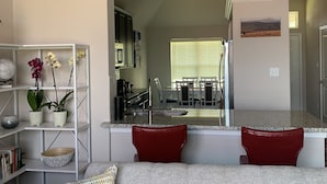 A modern living room with a gray sofa, red cushions, a white console table with decorative items, and a bookshelf. - Skip the gameday/ graduation gridlock (Bryan)