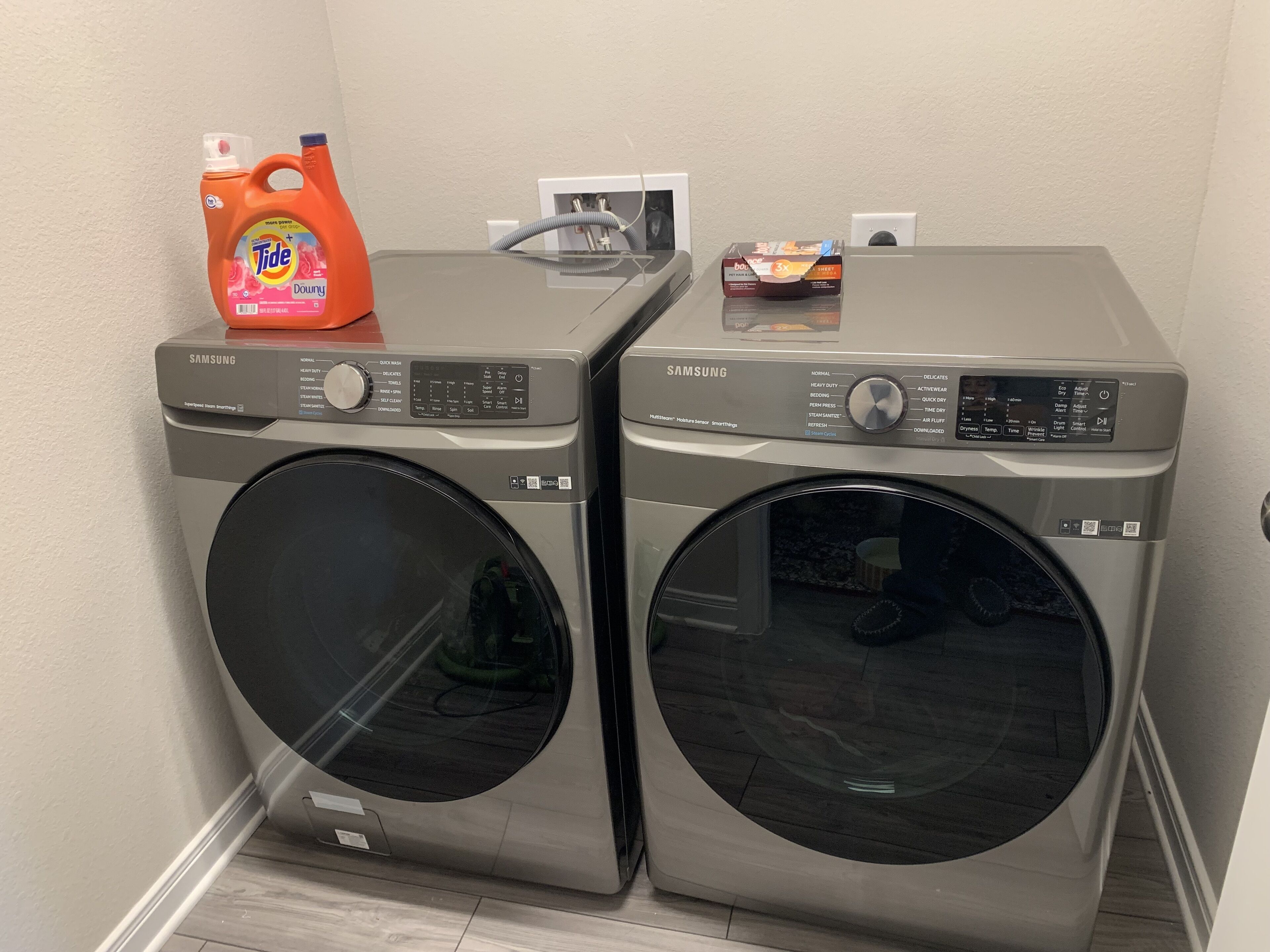 Dos lavadoras Samsung de carga frontal, con detergente Tide y una caja de bicarbonato de sodio encima.