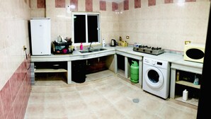 A compact kitchen with a refrigerator, sink, gas stove, and washing machine.