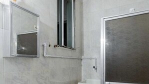 A bathroom with a toilet, a sink, a mirror, and a shower enclosure. - Luxury apartment by the sea (Rio de Janeiro)