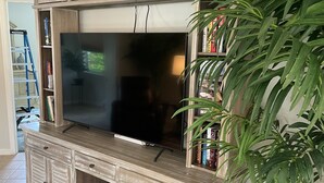A wooden entertainment center with a flat-screen TV, built-in shelves, and cabinets.