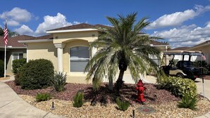A residential house with a garage, a palm tree, and a golf cart.