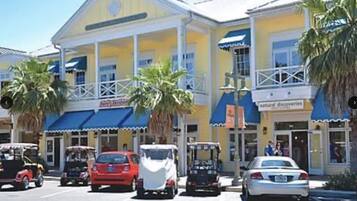 A building with a yellow facade, a blue awning, and palm trees in front.