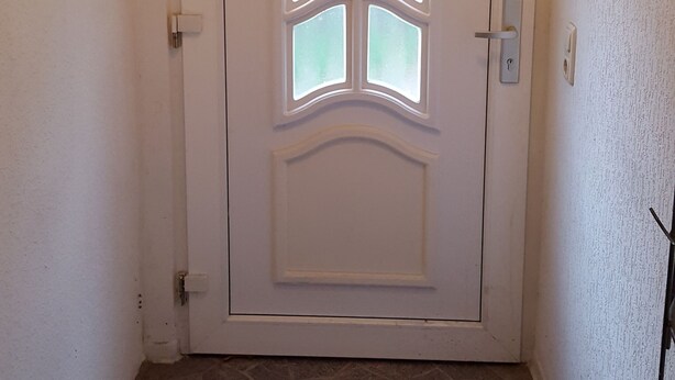 A white door with a decorative glass panel, a doorknob, and a metal handle. - FEWO-NEUBEEREN 2 (2 rooms, 7 single beds) (neubeeren)