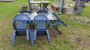 A patio area with a table and four blue chairs. - FEWO-NEUBEEREN 2 (2 rooms, 7 single beds) (neubeeren)