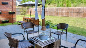 A patio with wicker chairs, a wooden table, and a hanging umbrella.