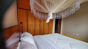 Une chambre à coucher avec un lit, une armoire en bois et un couvre-lit à baldaquin.