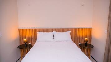 A neatly made bed with white linens, flanked by wooden headboards and two bedside lamps.