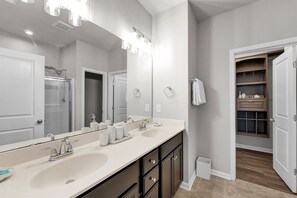 Une salle de bain moderne avec deux lavabos, un grand miroir et un dressing.