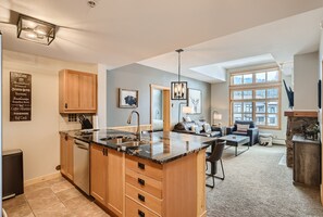 A spacious kitchen with a large island, wooden cabinets, and a built-in dishwasher.