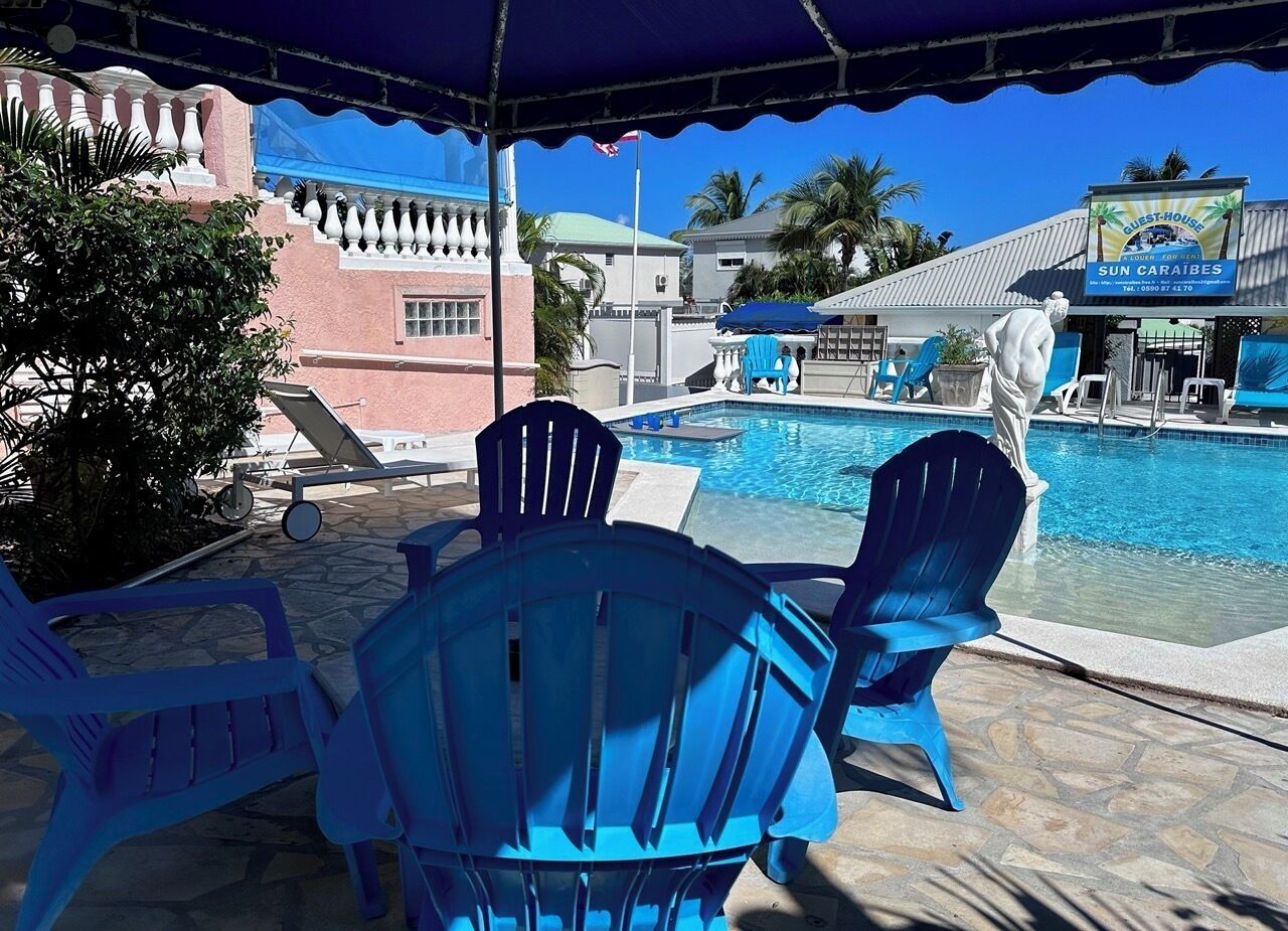 Un espace aménagé au bord de la piscine, avec des chaises bleues et une piscine.