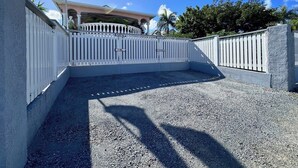 Un camino de entrada cerrado por una reja que conduce a un edificio con un asta que muestra las banderas estadounidense y haitiana.