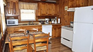 A compact kitchen with wooden cabinets, a microwave, a coffee maker, and a refrigerator.