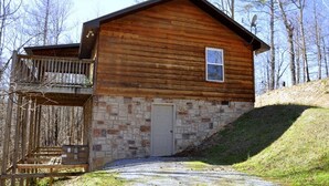 Eine Blockhütte mit Steinunterbau, einer Haustür und einem kleinen Balkon.