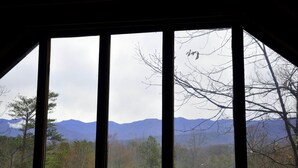 Ein Zimmer mit großem Fenster und Blick auf Berge und Bäume.