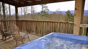 Ein Whirlpool auf einer Holzterrasse mit Blick auf die Berge.