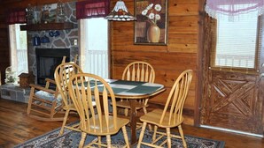 A wooden interior with a fireplace, a round table with chairs, and a patterned rug. - Romantic Secluded Cabin in Gatlinburg with Great Mountain View (Gatlinburg)
