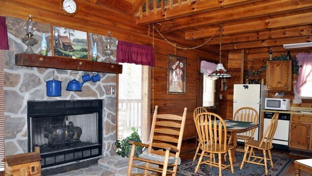 A cozy cabin interior with a stone fireplace, wooden dining table, and chairs. - Romantic Secluded Cabin in Gatlinburg with Great Mountain View (Gatlinburg)