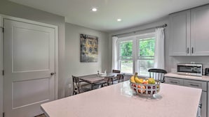 A kitchen with a large island, a dining table, and a window with curtains. - Cozy Arden Cottage, 2 Mi to Lake Julian Park! (Arden)