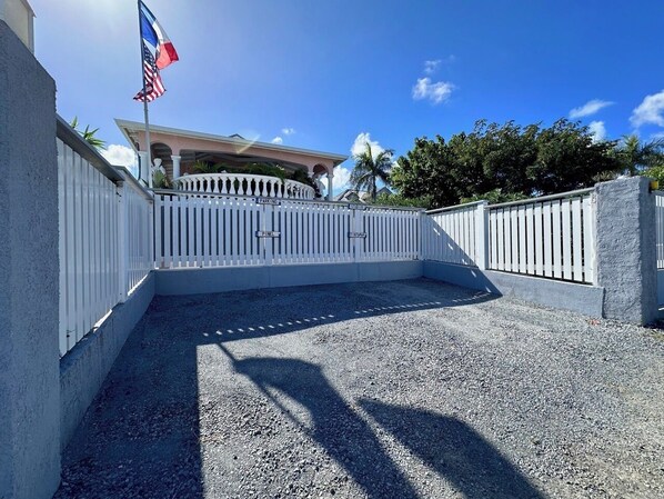 Une allée bordée de portails mène à un bâtiment sur lequel flotte un mât portant les drapeaux américain et haïtien.