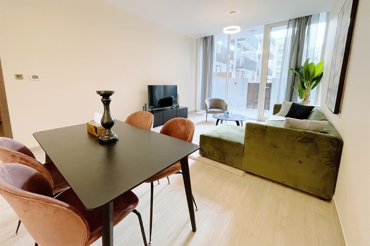 Uma sala de estar moderna com uma mesa de jantar, cadeiras, um sofá, uma TV e uma janela grande com vista.