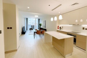 A modern kitchen with a central island, dining area with chairs, and a view to the outside. - Enchanting 1BDR Apt w/ Direct Pool & Gym Access (Arjan)