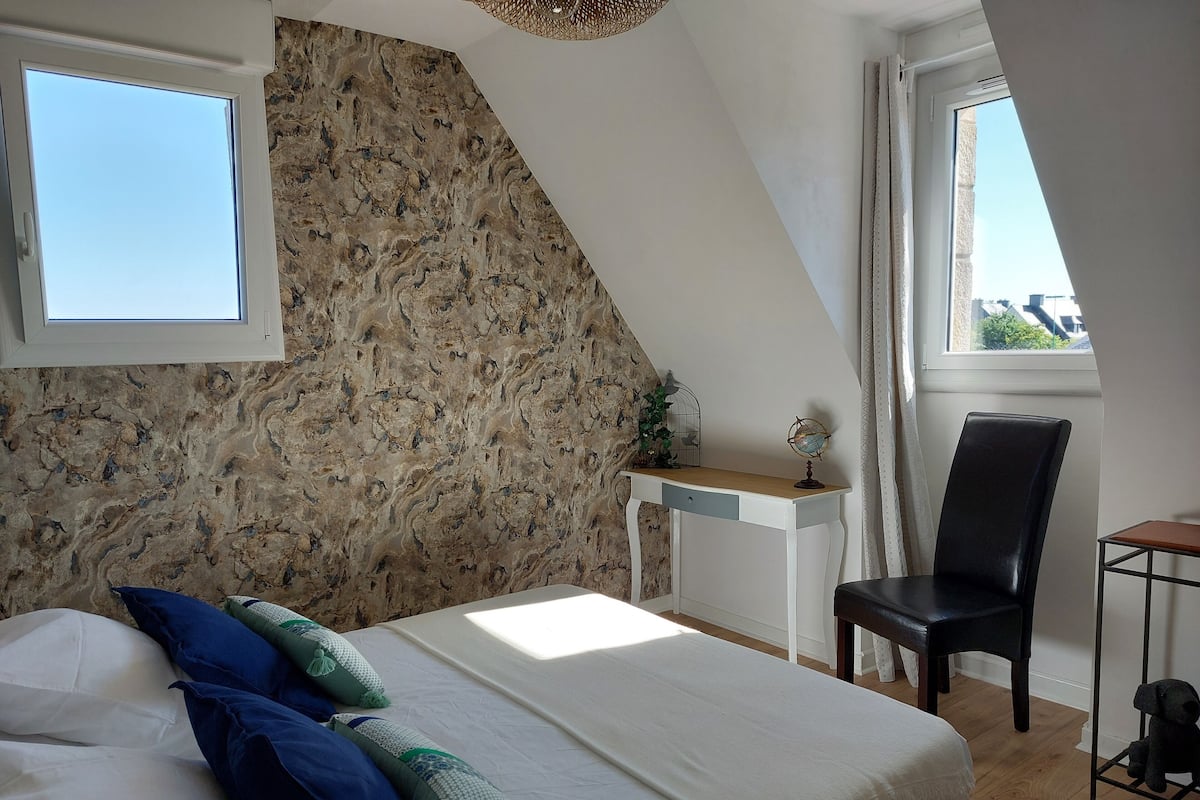 Ein Schlafzimmer mit Bett, Schreibtisch, Stuhl und Fenster.