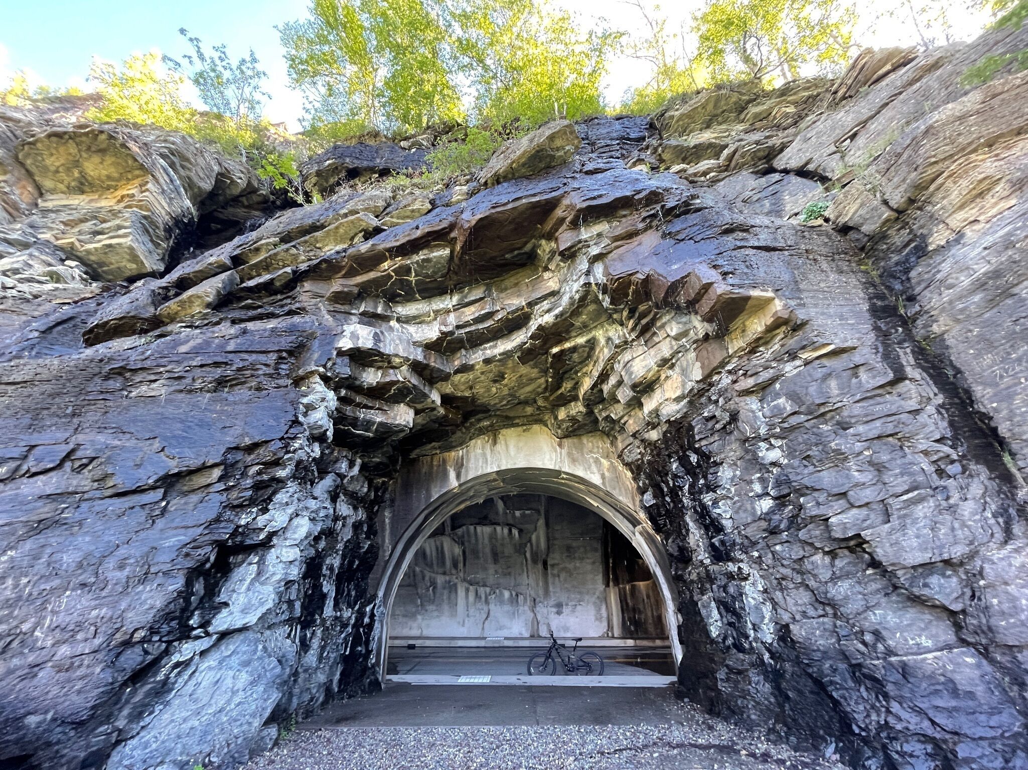 L’entrée d’un tunnel, avec un vélo garé à l’intérieur, le tout étant entouré de parois rocheuses.