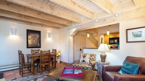 Una sala de estar acogedora con muebles de madera, un tapete estampado y un comedor con mesa y sillas.